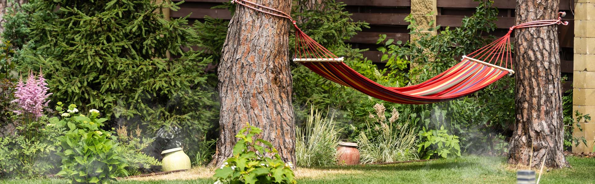 Commercial mosquito misting system hidden in bush in resort garden.